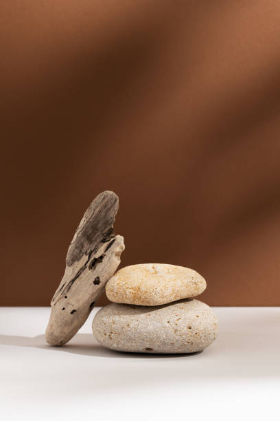 istock Empty stone podium with lights and shadows on brown background. Minimal backdrop. Round natural rock and piece of driftwood. Abstract pedestal or showcase for advertising. Minimal wabi sabi concept 1472289902