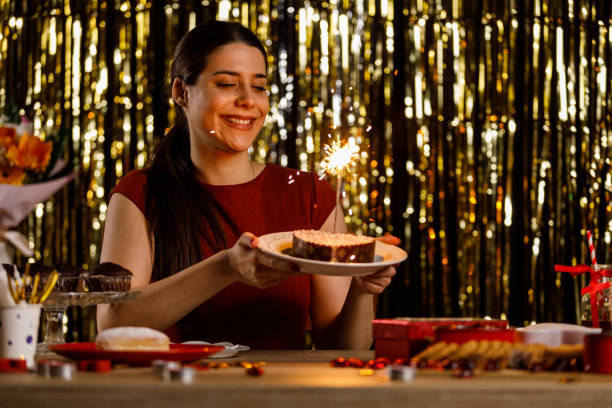 istock Young woman holding a heart shaped cake with sparklers inside burning 1472290185