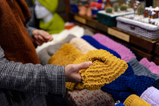 Close up of unrecognizable man choosing knitted scarf at market stall.