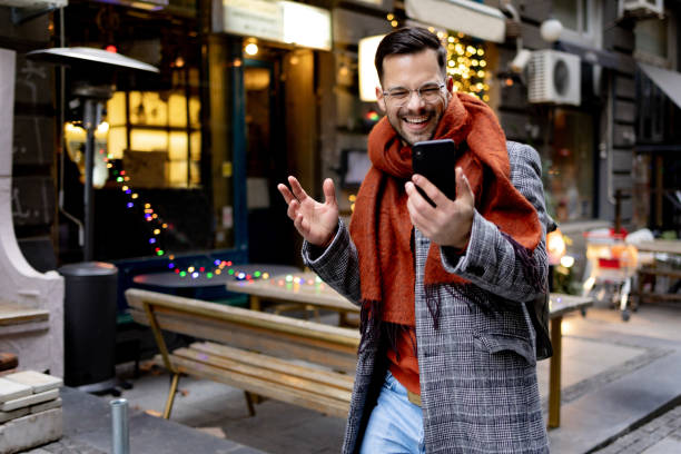istock Cheerful man having a video call over smart phone on the move. 1472291026