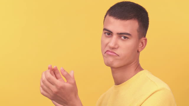Clap hands, face and male in a studio with a sarcastic facial expression and bravo hand gesture. Applause, praise and portrait of young man model clapping for well done by a yellow background.