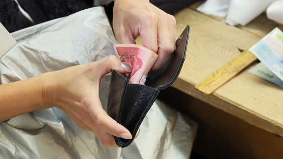 A woman takes Taiwan dollars out of her wallet and is about to pay