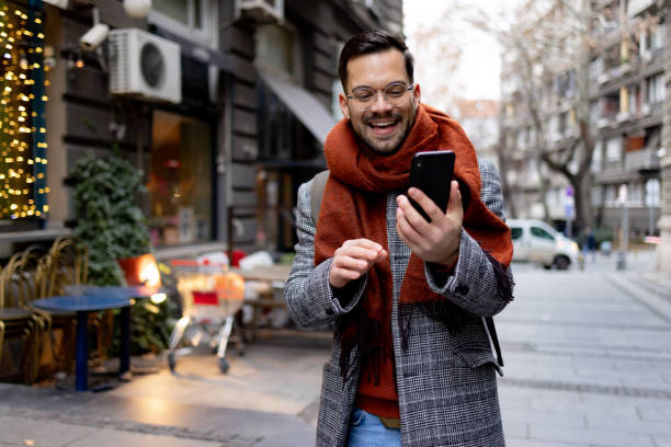 Happy male tourist using mobile phone while walking on the street.