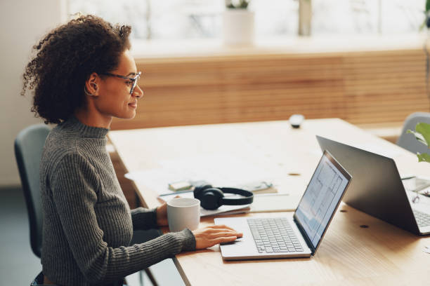 istock Young woman manager drinking coffee while working on laptop in coworking 1472293622