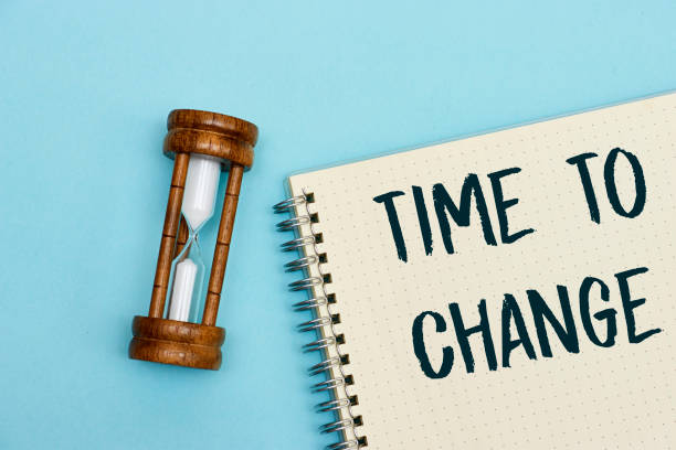 istock Time to change concept on notebook with hourglass on wood table as time passing concept. Life time passing. Meaning of life 1472297770