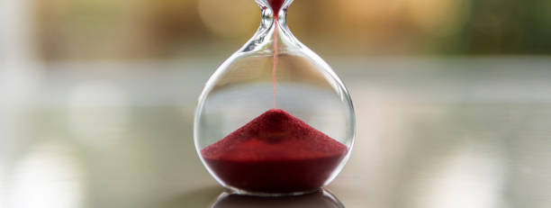 istock Red sand flows through the old-fashioned hourglass 1472297804