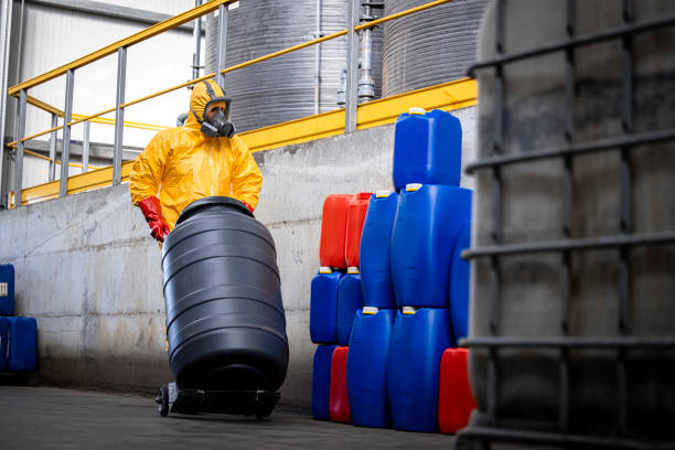 istock Worker wearing protective suit and gas mask while moving dangerous chemicals at modern chemical plant. In background large tanks reservoirs with acid. 1472300825