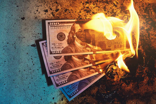 Three $100 banknotes burning, amid fire, flames and ash stock photo