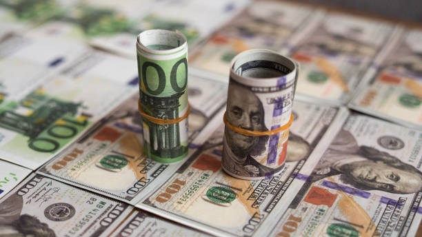 istock Dollar and euro roll stands on banknotes 1472302246