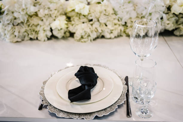 Serving, setting table. Plate decorated linen black napkin and silverware cutlery, knife, fork, glasses. flat lay. top view. Closeup. Wedding set up, dinner table reception. Birthday, baptism, event.