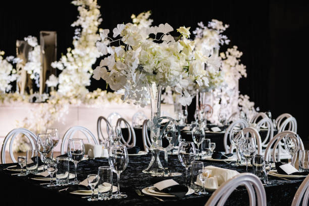 mise en place du mariage, réception à table dans la zone de banquet sur la fête. composition florale au centre de la table. nappe noire. décoration de banquet dans le restaurant hall. décor argenté de luxe. réglage. vue latérale - floral centerpiece photos et images de collection