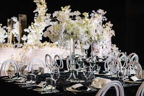 Wedding set up, dinner table reception in banquet area on party. Flower composition in center of table. Black tablecloth. Banquet decoration in hall restaurant. Luxury silver decor. Setting. Side view