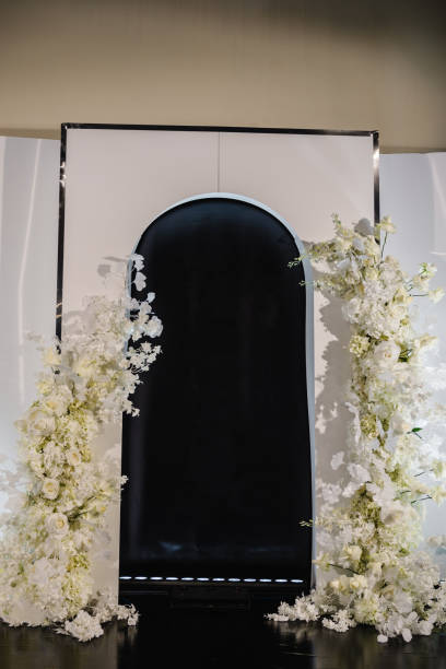 istock Wedding reception for luxury ceremony in hall restaurant. Copy space. Black photo wall, arch place decorated petal, flower. Celebration baptism concept. Trendy decor for birthday party in banquet area 1472305569
