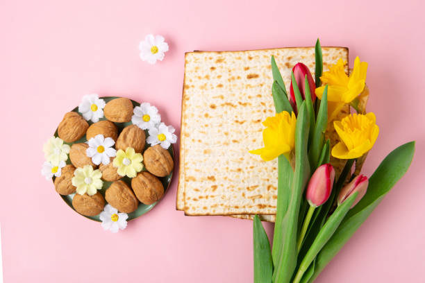 istock Passover Greeting Card with Matzah, Nuts and Spring Flowers on Pink Background. 1472306142