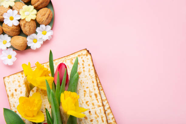 istock Passover Greeting Card with Matzah, Nuts and Spring Flowers on Pink Background. 1472306199