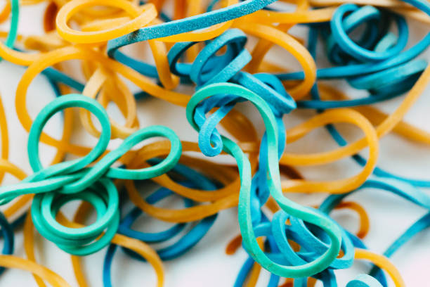 Macro close up color image depicting a collection of colored rubber bands on a white background.