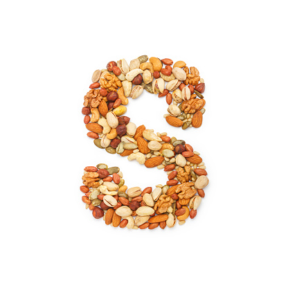 Letter S which is laid out from different nuts, isolated on white background. Top view, flat lay