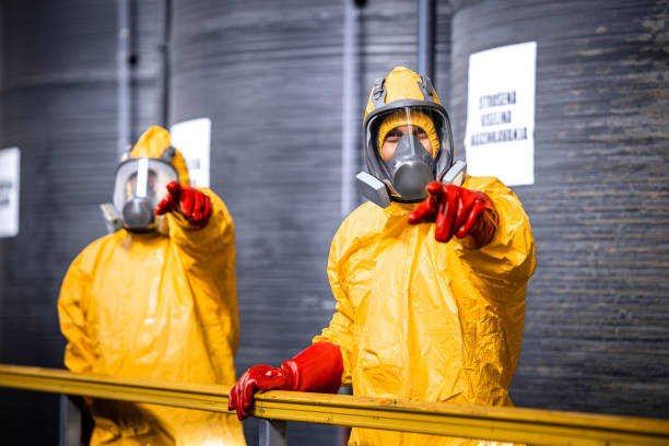istock Factory supervisor in protection equipment and gas mask pointing fingers and explaining process of chemical production to the trainee. 1472307664