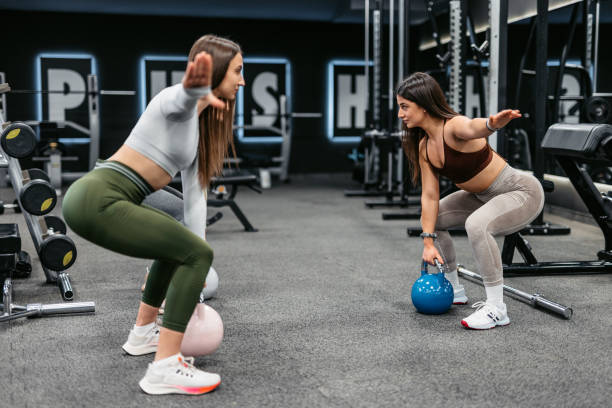 istock Two Young Women Training With Kettlebells Together At The Gym 1472309197