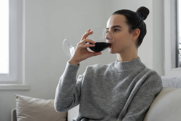 istock Woman sitting on couch having glass with red wine 1472310026