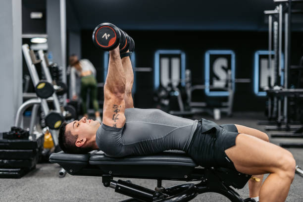 istock Young Man Training With Dumbbells At The Gym 1472310274