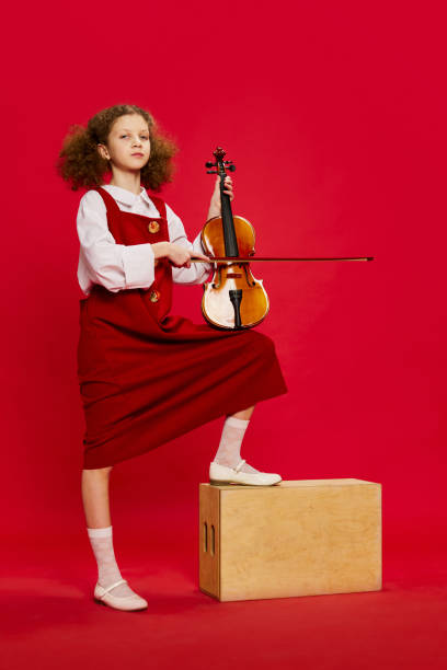 Portrait of little girl, talanted musician wearing huge mother's sundress posing with violin isolated over magenta background. Education, music, classic art, new vision, fun concept Portrait of little girl, talanted musician wearing huge mother's sundress posing with violin isolated over magenta background. Pop art, education, music, classic art, new vision, fun concept pop art photos stock pictures, royalty-free photos & images