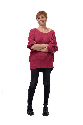 full length portrait of standing woman in tight jean pants looking at camera with arms crossed on white background