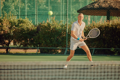 Fitness, play or old man on tennis court in game or practice match in retirement in summer for wellness. Healthy mature male person running with racket in cardio training, workout or outdoor exercise