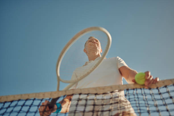 fitness, bajo y hombre en una cancha para tenis, entrenamiento y práctica para una competición. jugador feliz, deportivo y de edad avanzada listo para comenzar un deporte para el ejercicio, la actividad física y el pasatiempo en la jubilación - tennis senior adult adult mature adult fotografías e imágenes de stock