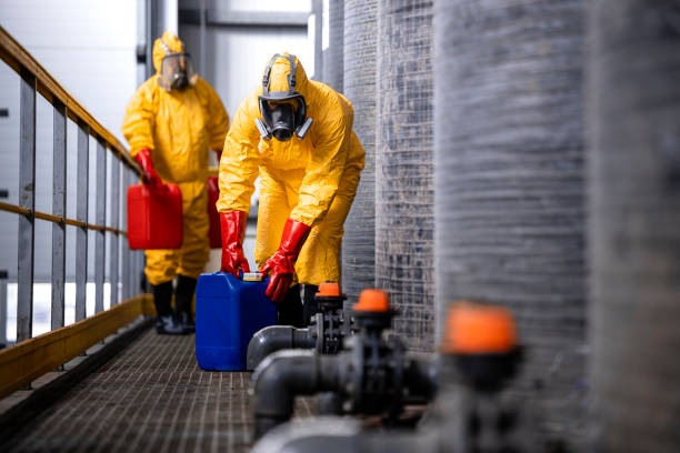 istock Experienced and trained workers with gas masks handling dangerous material inside chemicals factory. 1472314277