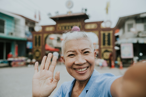 Thai senior hipster taking a selfie while enjoy her retirement life and traveling in her goal destination.