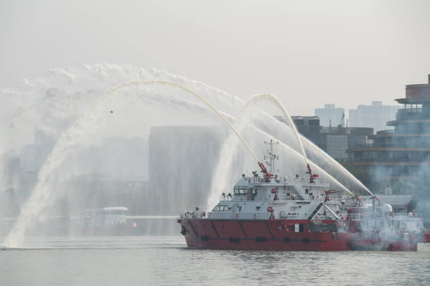 пожарная лодка распыляет воду на реке - fire boat стоковые фото и изображения