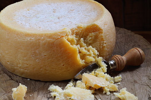 Round white homemade goat's milk cheese on wooden board.