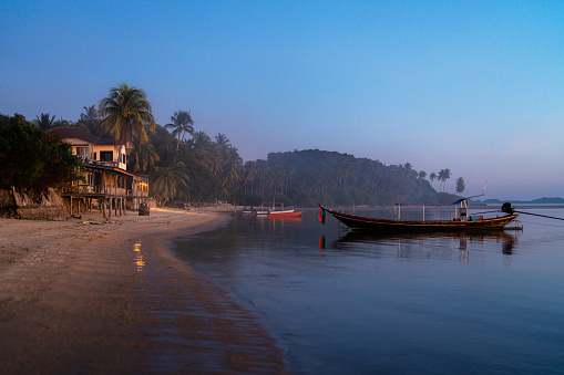 Beautiful Anjuna beach in the northern Goa, India. Popular beach vacations destination in Goa with blue Arabian Sea waves, rocks, and typical beach cafe.