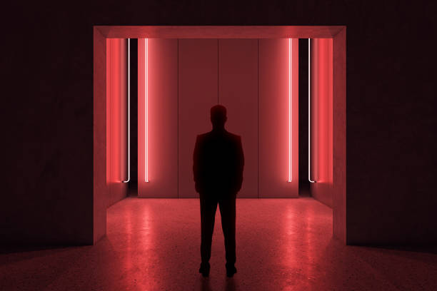 istock Back view of man standing in abstract red room interior. 1472316871