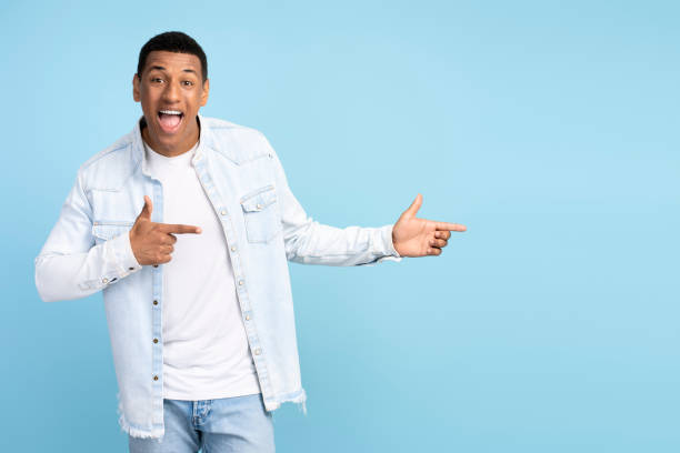 istock Advertise here. Positive man pointing finger away paying your attention at empty space 1472317495