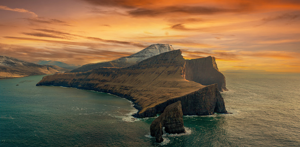 Drangarnir, Vagar, Faroe Islands - March 9, 2023; One of the most unique sights in the Faroe Islands are “Drangarnir”. Drangarnir are two sea stacks between Vagar and the islet Tindhólmur. The distinct names of Drangarnir are Stóri Drangur and Lítli Drangur which can be translated into Large- and Small sea stack. The large sea stack is 230 feet tall.