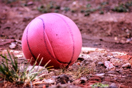 a red plastic ball toy in the corner of the field