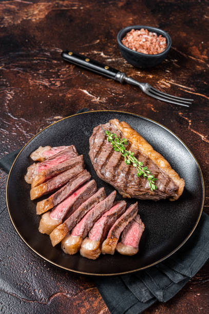 sliced grilled medium rare top sirloin beef steak on a plate. dark background. top view - picanha beef meat rare imagens e fotografias de stock