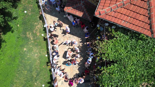 Aerial view of a wedding ceremony with people dancing in circle - Macedonian traditional dance
