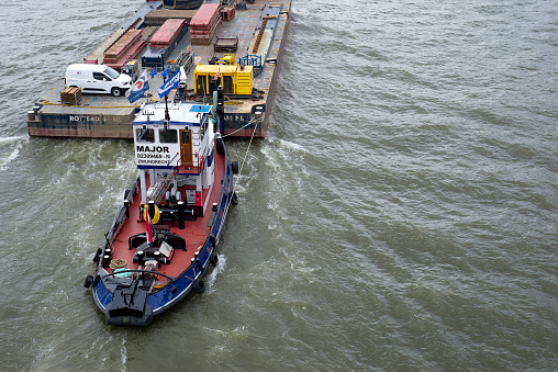 Rotterdam, The Netherlands- June 2020; High angle view of a inland barge with containers stacked high in its cargo hold on the Maas River