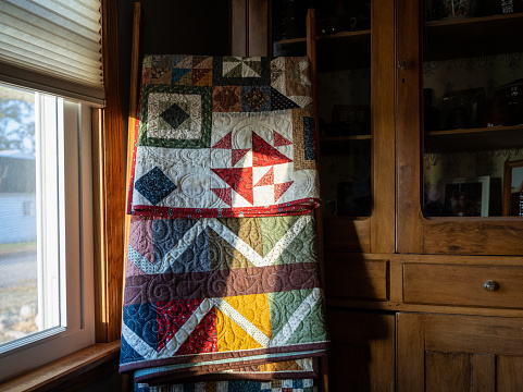 Red, white, brown, and blue patchwork quilt on display. The fabrics used all have tiny flowers on them.