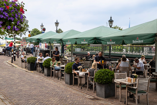 Muiden, Netherlands, July 12, 2021; People enjoy the terrace along the river Vecht in the center of Muiden.