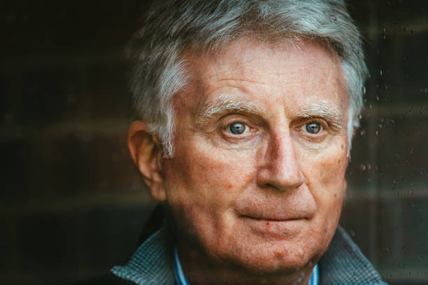 istock Vulnerable senior man looking out of rainy window 1472338856