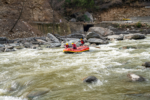 10-02-2019 Himachal Pradsk, India. Rafting on the river Beas: big stones in the water. Up the road - a rubber boat on the roof of a car (this is how the rubber boat gets to the starting point up the river). An SUV with a rubber boat is moving up the road