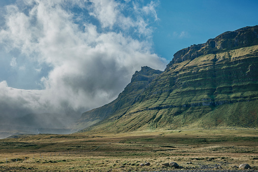 Kirkjufell mountain in Snaefellsnes, Iceland. Cloudscape over field and mountains.