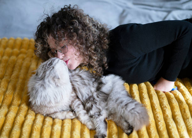 istock Woman kissing her cat on sofa 1472345178