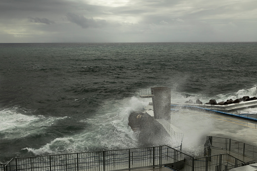 An image of a stormy Atlantic sea battering a coastguard viewing point on the coast of Madeira, Portugal.