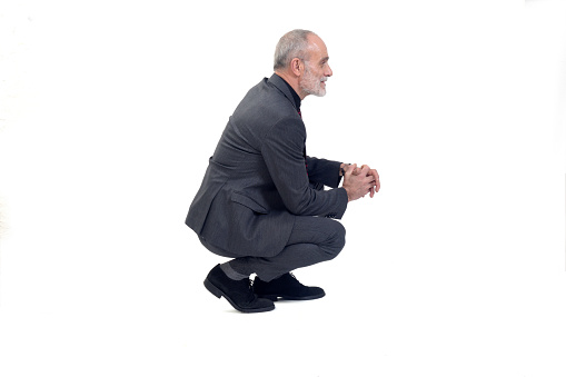 side  view of a man with suit squatting on white background