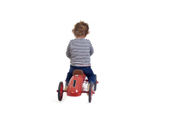 A young child rides a colorful plastic toy car at a baptism or family celebration, symbolizing the joy, innocence, and playful moments of childhood during festive family gatherings.